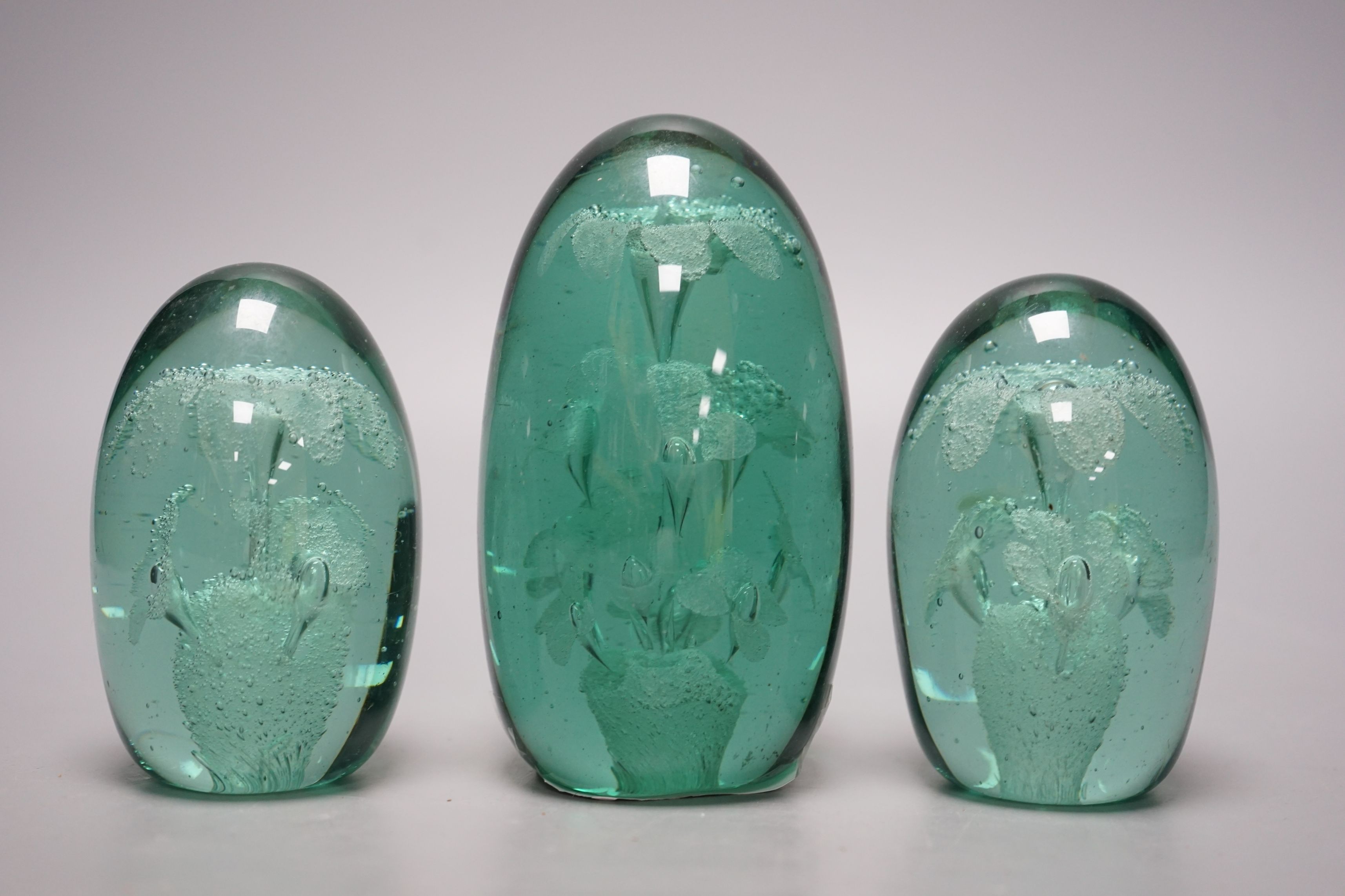 Three green glass dump paperweights, tallest 14cms high